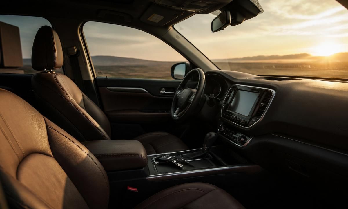 Front seats and center console of a well-appointed SUV interior at sunset