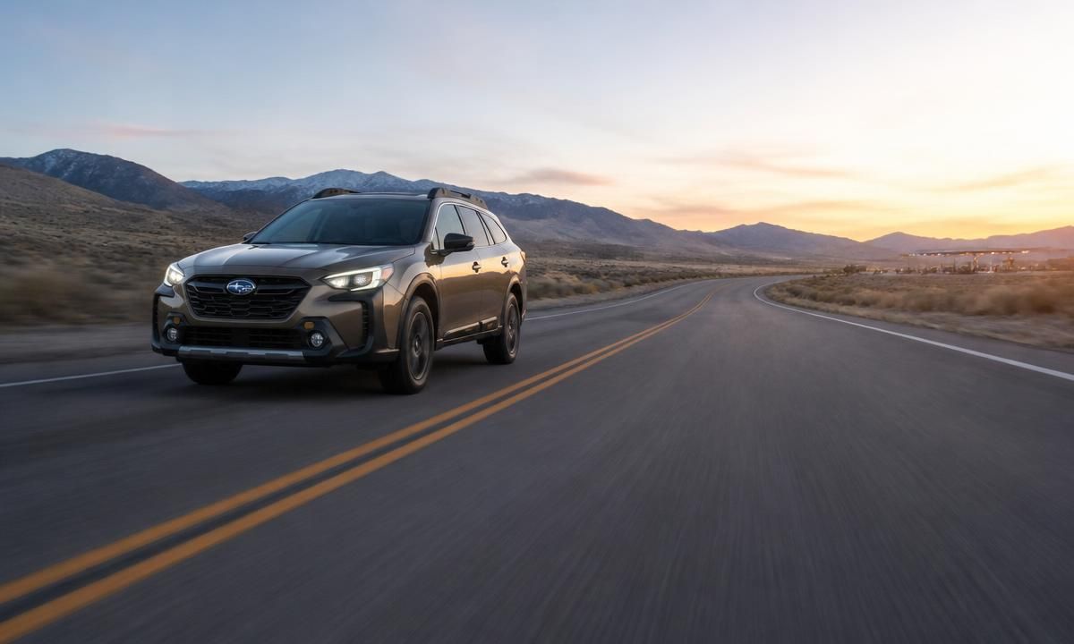 2026 Subaru Outback driving on a desert highway at dusk