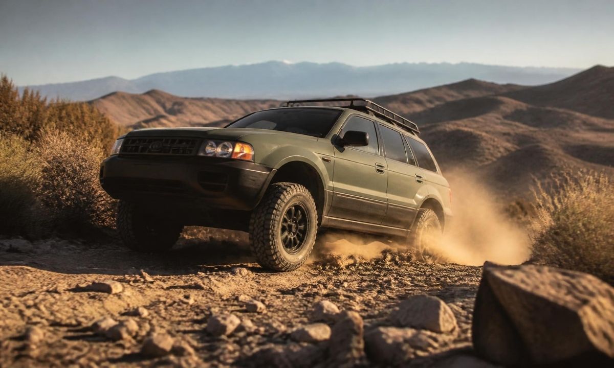 Green off-road-equipped Subaru Outback Wilderness driving on a rocky desert trail