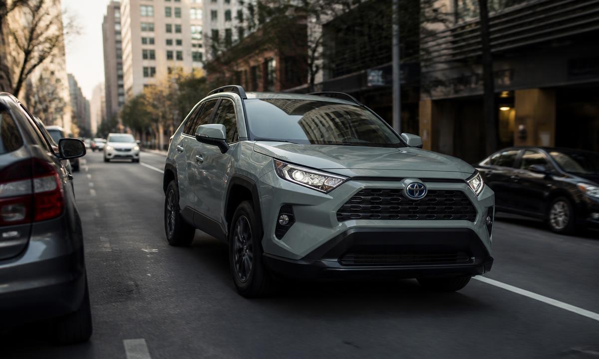 Toyota RAV4 Hybrid driving through city traffic on a tree-lined street