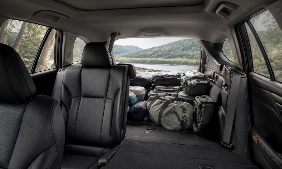 Loaded rear cargo area of a Subaru Outback with the rear seats folded and duffel bags stacked inside