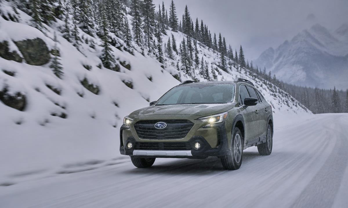 Subaru Outback driving on a snow-covered mountain road in winter conditions