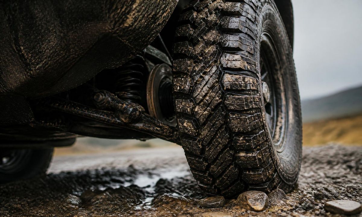 Close-up of a muddy Subaru all-terrain tire gripping wet gravel and rock
