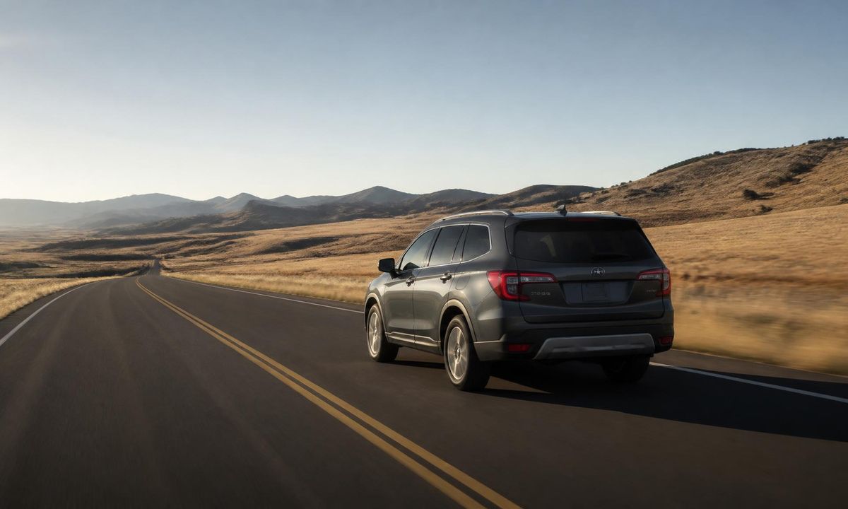 Subaru driving on open, dry highway through golden rolling hills under a clear sky