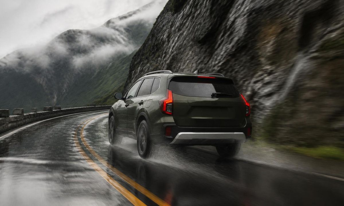 Green Subaru Outback tracking through a wet corner on a misty mountain highway